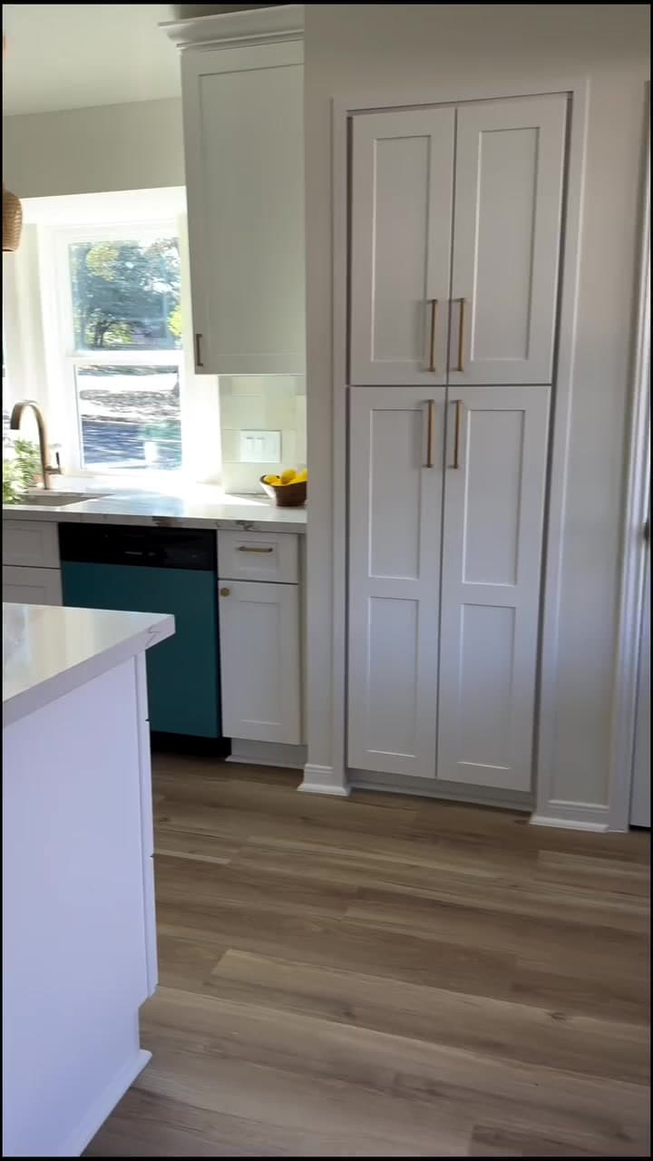 Finished ceiling-height white kitchen storage beside the sink and island