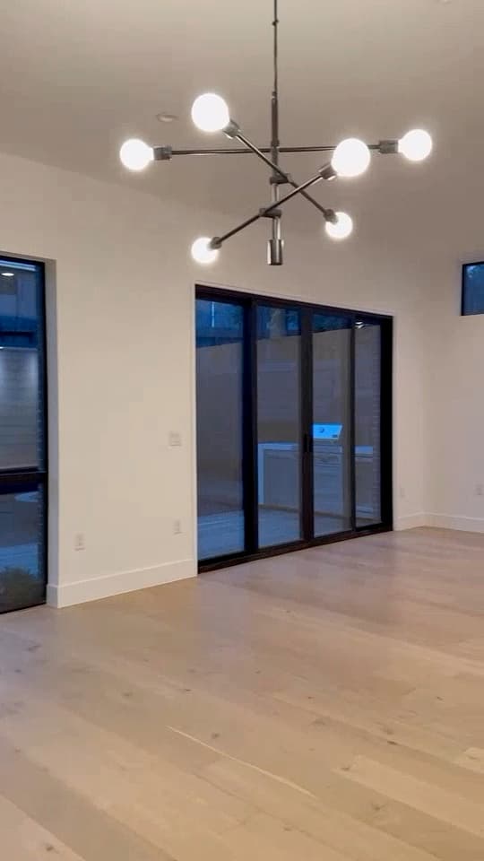 Adjoining dining area with light flooring, black-framed doors, and modern lighting in the same New Life kitchen project
