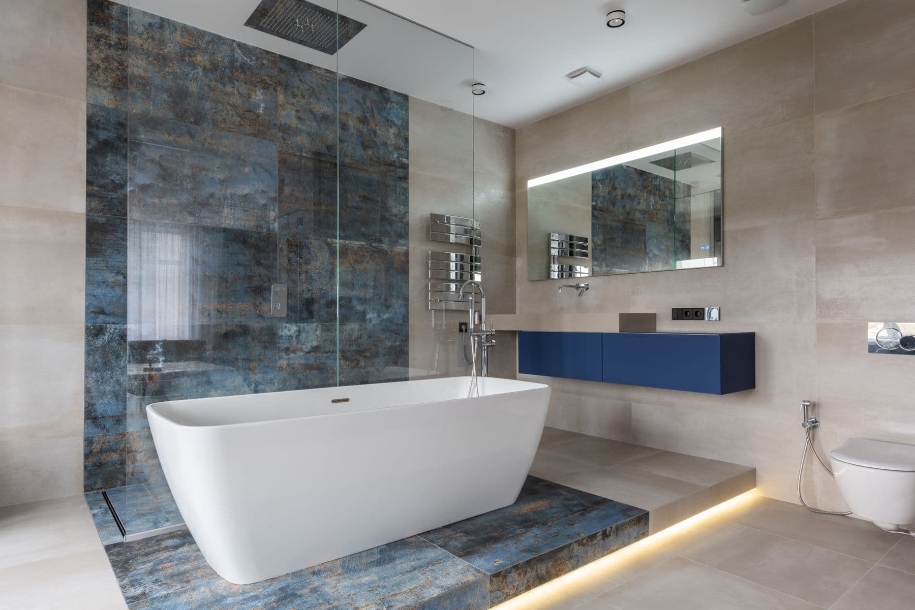 Modern bathroom inspiration with a freestanding tub, glass shower, blue vanity, and large-format tile