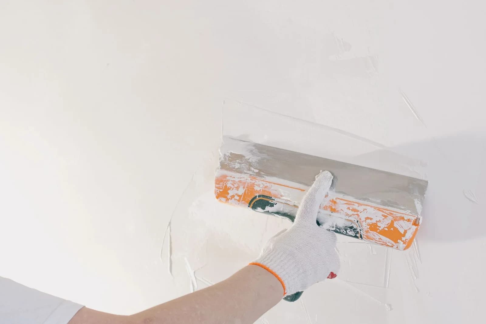 Close-up of joint compound being smoothed across an interior wall during drywall finishing