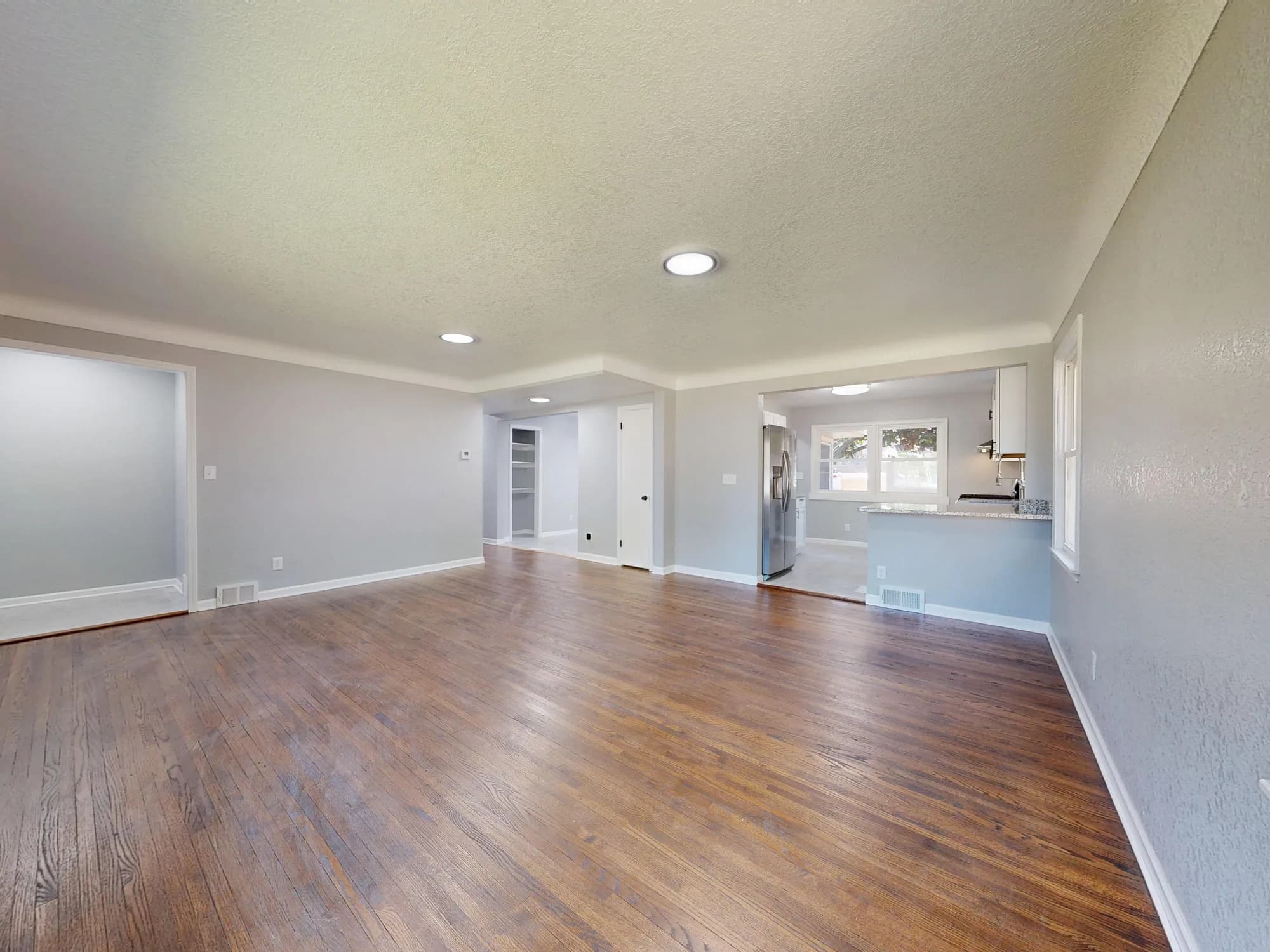 Bright open living space with hardwood flooring extending into connected rooms